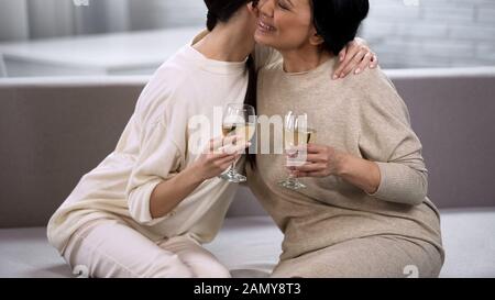 Belle amiche femminili che si abbracciano riposando sul divano e bevendo bevande gassate Foto Stock