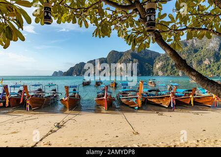 In legno tradizionali barche longtail parcheggiata in una spiaggia di Isola di Phi Phi. Acqua limpida e pulita spiaggia. Foto Stock