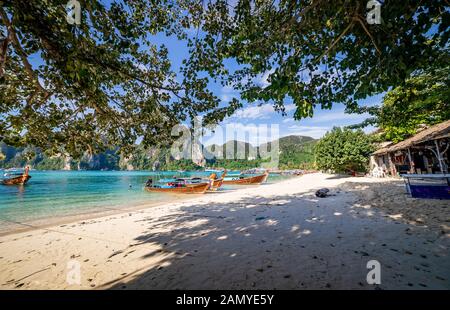 In legno tradizionali barche longtail parcheggiata in una spiaggia di Isola di Phi Phi. Acqua limpida e pulita spiaggia. Foto Stock