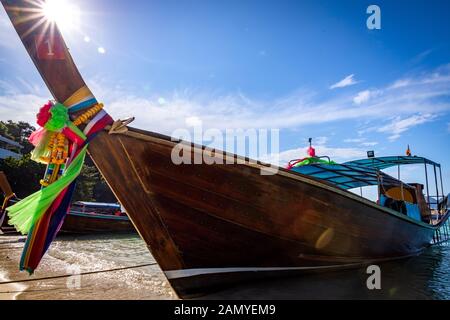 In legno tradizionali barche longtail parcheggiata in una spiaggia di Isola di Phi Phi. Acqua limpida e pulita spiaggia. Foto Stock