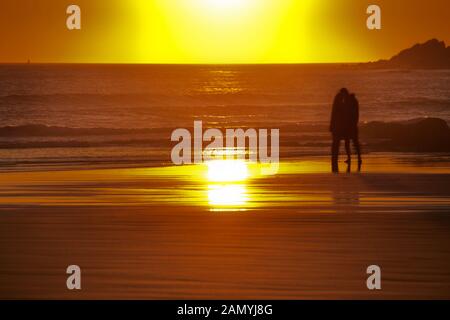 Giovane baciare sulla Croyde Bay spiaggia al tramonto Foto Stock