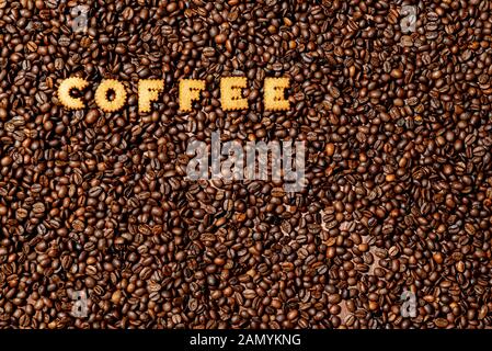 La parola caffè fatto da biscotto lettere al buio su un chicco di caffè sfondo - Immagine Foto Stock