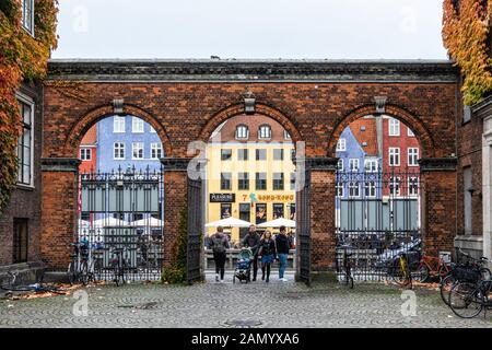 Vista di Nyhaven colorati edifici attraverso Charlottenborg fu palazzo in mattoni ingresso arcuato in Copehagen, Danimarca Foto Stock