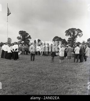 1965, storico, una preghiera cristiana al di fuori servizio a una carovana del rally, England, Regno Unito, con adulti e bambini in piedi in cerchio holding Bibbie. Foto Stock