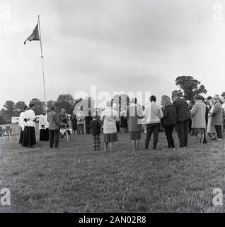 1965, storico, una preghiera cristiana al di fuori servizio a una carovana del rally, England, Regno Unito, con adulti e bambini in piedi in cerchio holding Bibbie. Foto Stock