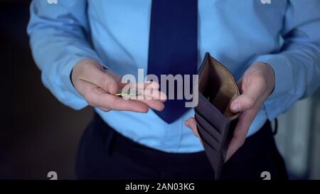 L’uomo contando le monete lasciate al prossimo stipendio, basso reddito, mancanza di denaro, povertà Foto Stock