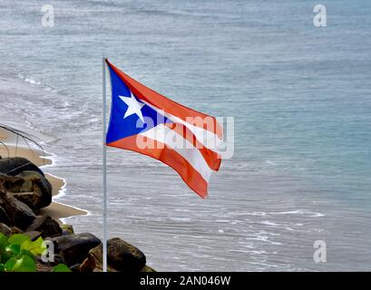 La bandiera di Puerto Rico vola su un oceano spiaggia di Rincon, PR. Copia dello spazio. Foto Stock