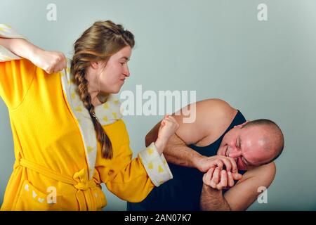 Moglie aggressiva abusi la sua posizione e batte il suo marito. Foto Stock