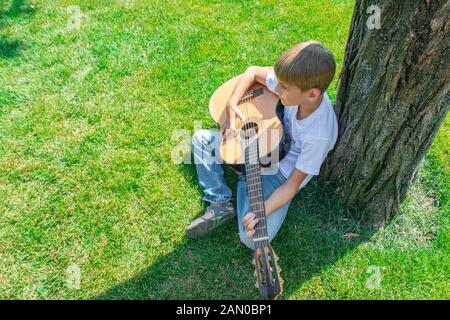 Il bambino gioca la chitarra in natura, vista dall'alto. Foto Stock