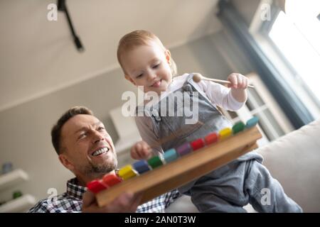 Carino bambina cercando felice palying con xilofono Foto Stock