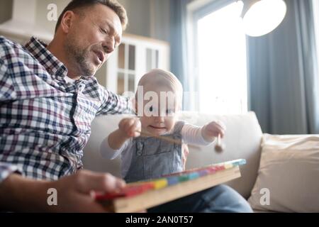 Carino bambina cercando occupato a giocare con xilofono Foto Stock