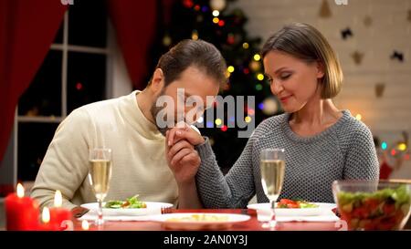 Uomo baciare la mano della signora con attenzione, avendo data romantica alla vigilia di Natale, coppia amorevole Foto Stock