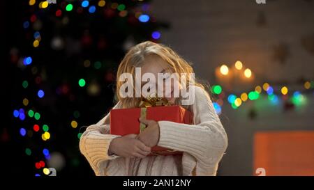 La ragazza eccitata abbraccia la scatola del regalo, regalo di Natale atteso a lungo, i sogni si avverano Foto Stock