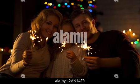 Ritratto di famiglia felice con luci del bengala, celebrando insieme il Natale Foto Stock