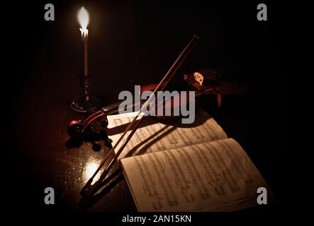 Violino e note musicali di close-up. Marrone Vintage violino e archetto su sfondo di legno. Simbolo della orchestra di musica. Foto Stock