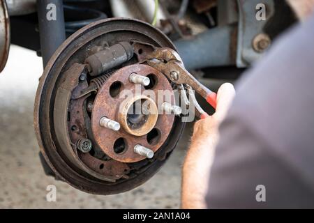 Uomo con pinze opere esposte auto frena durante pastiglie freno job Foto Stock