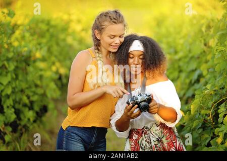 Ragazza con una vecchia foto fotocamera sul film - le fanciulle felici amici prendendo alcune foto esterni - vivaci colori di sfondo Foto Stock