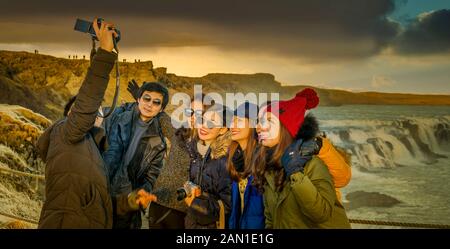 Turisti provenienti dall'Asia che scattano foto alle cascate di Gullfoss, Islanda Foto Stock