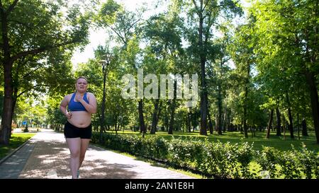 Donna obesa difficile da jog, estenuanti allenamenti per bruciare grasso, insicura ragazza sconvolta Foto Stock