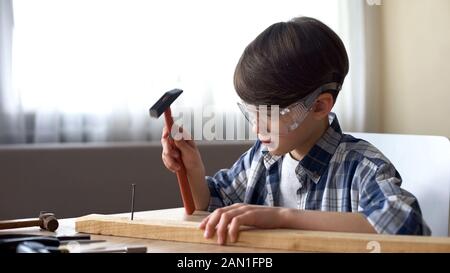 Carino bambino martellante chiodo in legno Plank, hobby e tempo libero, workshop Foto Stock