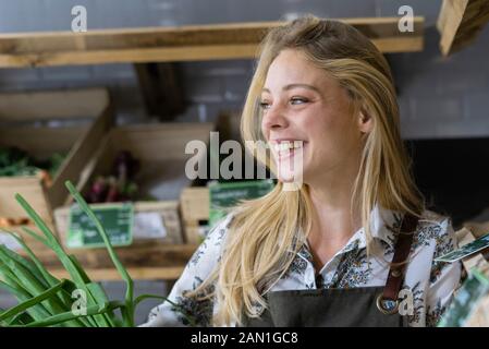 Giovane donna sorridente che tiene la cipolla della molla nel cestino di vimini Foto Stock