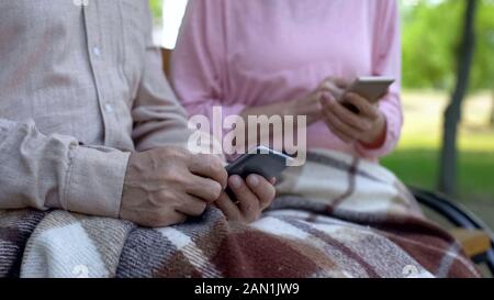 Il vecchio uomo e donna gli smartphone di contenimento di guardare video, nursing home Tempo libero Foto Stock