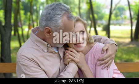 Felice coppia senior abbraccia nel parco, abbracciando uomo donna amore fino alla vecchiaia Foto Stock