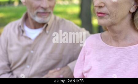 Bello pensionato guardando bella donna matura con interesse seduto in posizione di parcheggio Foto Stock