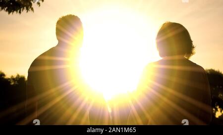 Persone anziane marito e moglie di ombre in sunset illuminazione, rilassante parco insieme Foto Stock