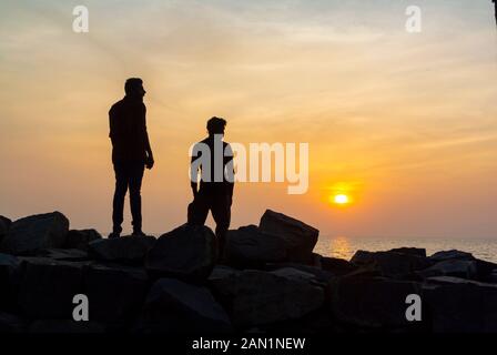 Kovalam, Kelara/ India, Silhouette di due uomini al mare durante il tramonto Foto Stock