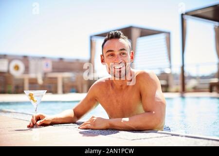 Un uomo che si gode un martini in piscina. Foto Stock