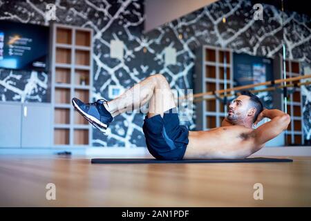 Un uomo che fa crunches addominali in una palestra Foto Stock