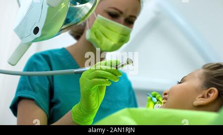 Dentista preparando per praticare un dente malato, brave ragazza adolescente in attesa per la procedura Foto Stock