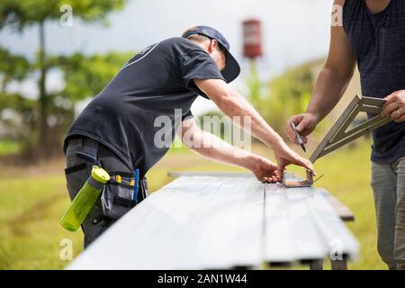 Due uomini che segnano misure su escursione in acciaio per pannelli solari. Foto Stock