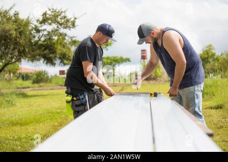 Due uomini preparano escursioni in acciaio per l'installazione di pannelli solari. Foto Stock