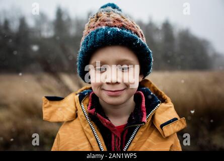 Ragazzo che guarda fuori una finestra che tiene una ciotola di cereali a Natale Foto Stock