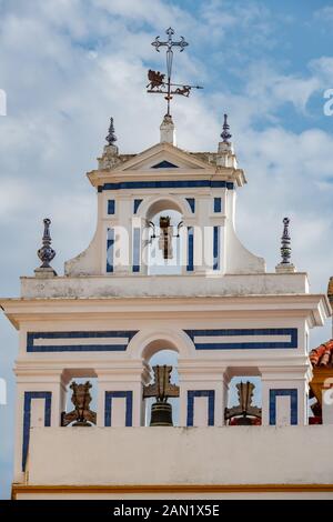 Un ferro battuto croce e ornato banderuola in cima alla cella campanaria imbiancate di Iglesia Santiago nella Plaza de Jesus De La Redencion a Siviglia Foto Stock