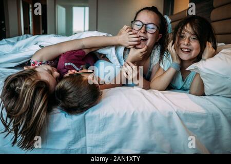 i bambini che giocano sul letto dell'hotel mentre sono in vacanza Foto Stock