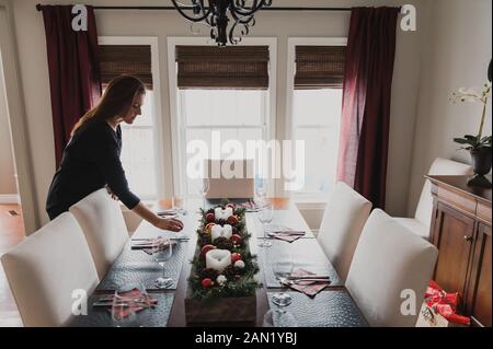 Donna che mette un bicchiere su un tavolo da pranzo set per una cena di festa. Foto Stock