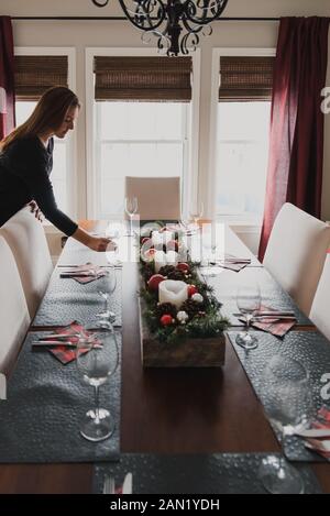 Donna che mette un bicchiere su un tavolo da pranzo set per una cena di festa. Foto Stock