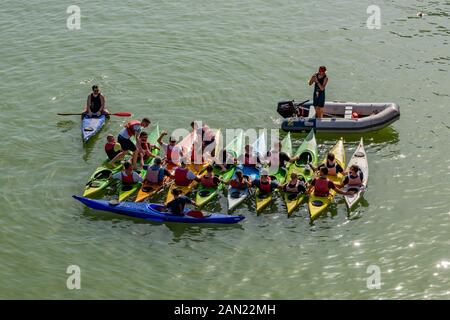 Kayak, in un tour di Siviglia in kayak, pratica mantenendo il loro equilibrio mentre attraversano da barca a barca sul fiume Guadalquivir a Siviglia. Foto Stock