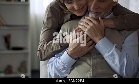 Felice anziana sposa abbracciando il marito, uomo tenendo le sue mani, rapporti armonici Foto Stock