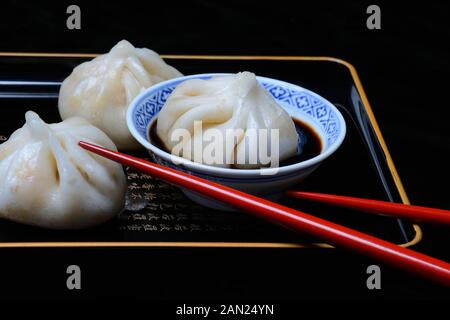Dim Sum in cinese ciotola con la salsa di soia, gnocchi ripieni, rosso bacchette, Germania Foto Stock