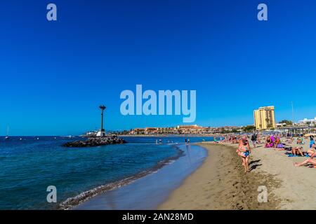 Los Christianos, Tenerife, Dicembre 10, 2019, la gente camminare accanto alla spiaggia di sabbia bianca e posa sulla terra per godersi il sole e il caldo Foto Stock