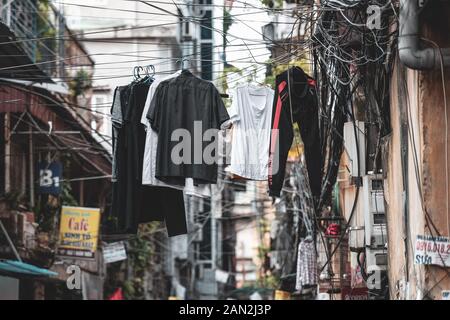 Hanoi, Vietnam - 18 Ottobre 2019: vestiti appesi da linee di alimentazione in un vicolo di Hanoi, Vietnam Foto Stock