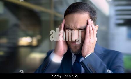 L'uomo soffre di mal di testa, templi di massaggio, emicrania dizzy effetto, close up Foto Stock