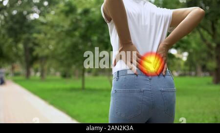 La donna si sente dolore alla schiena quando passeggiate nel parco, infiammazione dei reni, artrite Foto Stock