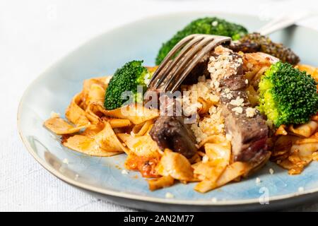 Tagliatelli con fette di bistecca su una piastra Foto Stock