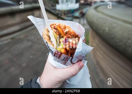 POV di un uomo di contenimento e mangiare fuori del giroscopio. Tradizionale greco per il fast food Foto Stock