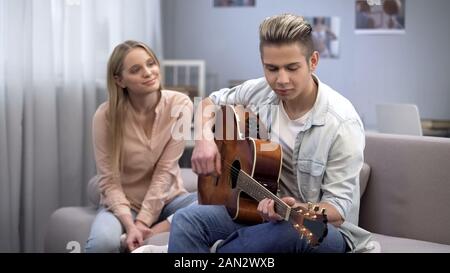 Ragazzo adolescente in amore a suonare la chitarra alla ragazza di conquistare il suo cuore, romanticismo Foto Stock